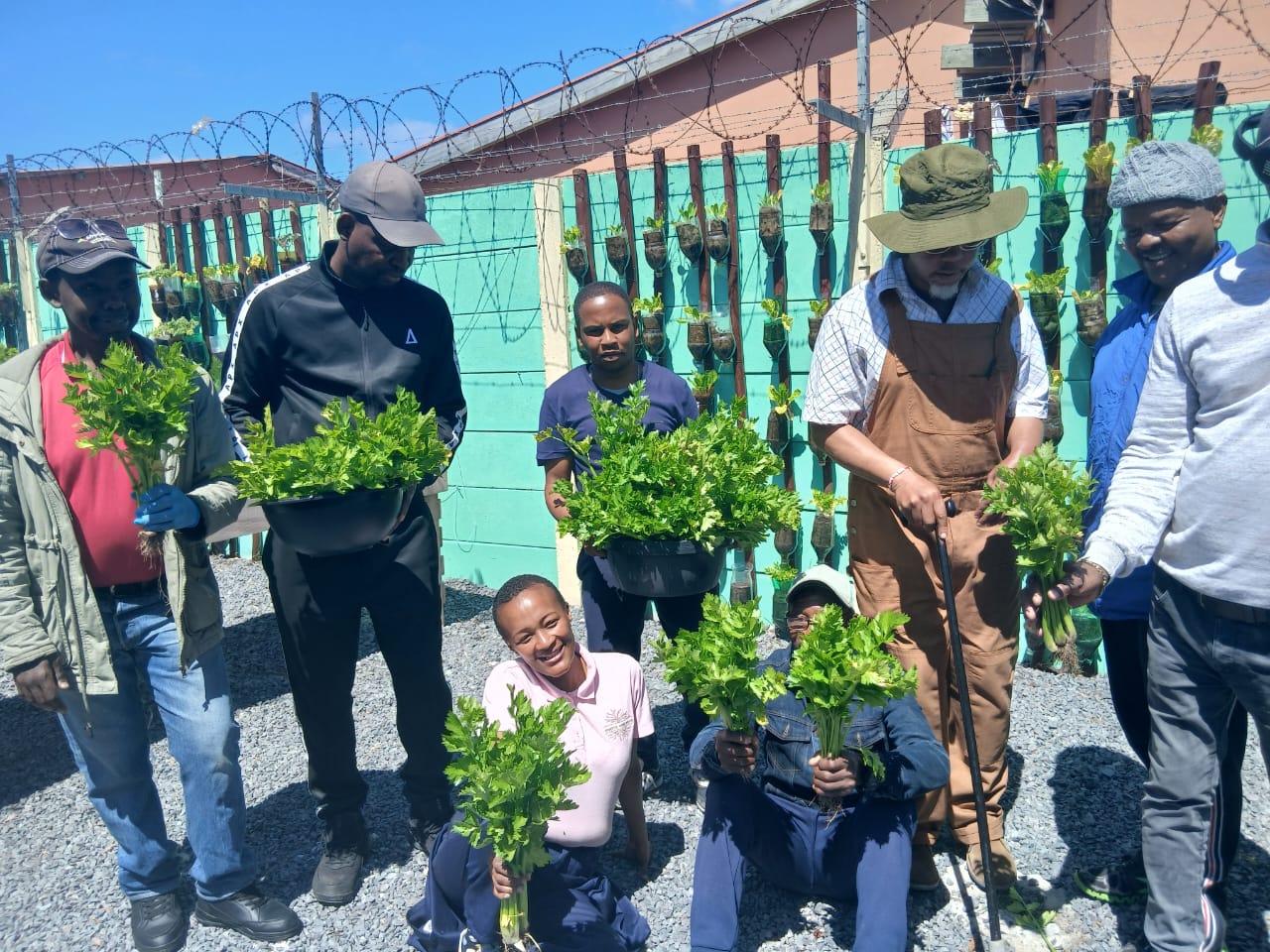 Participants and supporters holding fresh greens in the garden area
