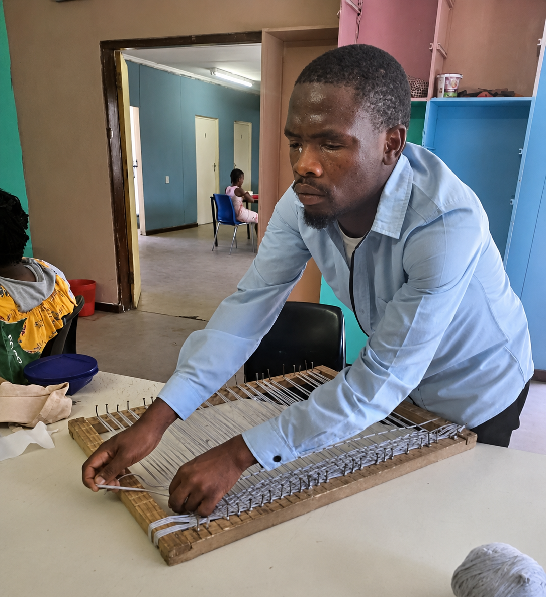 A person working with a handmade loom at Tembaletu